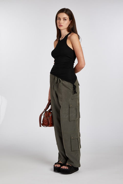 Chic and elegant black racerback tank top with an asymmetric hem paired with a baggy green cargo pant. Made from soft, stretchy, and sustainable fabric for a comfortable and versatile fit.