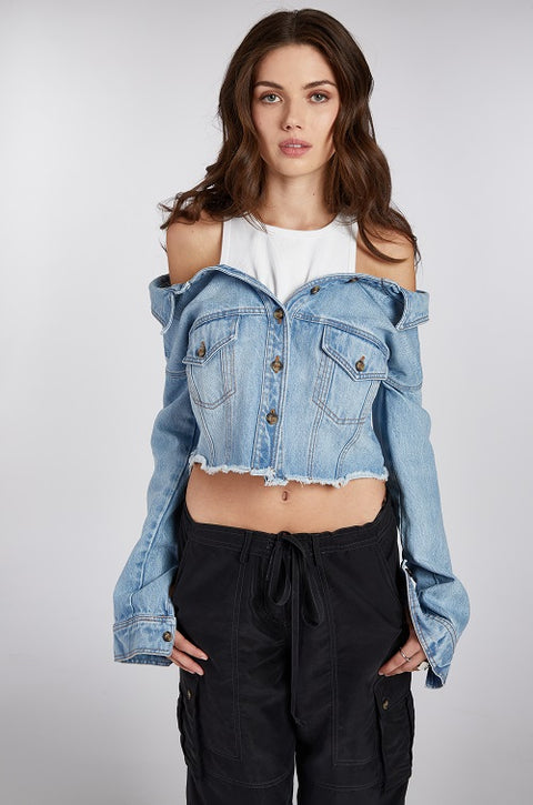 Close up of off-shoulder denim jacket with a built-in white ribbed racerback tank top, paired with drapey, baggy black cargo pants for an effortlessly cool look. Crafted from premium Italian denim in a light wash, this slouchy yet elegant 2-in-1 top features a slightly cropped fit, making it the perfect transitional outfit. Designed for versatility, it’s ideal for summer nights or layering through the seasons.
